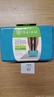 Front side of the Gaiam tri-colour yoga block packaging showing the brand name, tri-colour label, and a photo of the block in use.