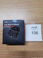 Original packaging of Otium PowerPods wireless earbuds on wooden surface with auction label.