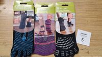 Set of three Gaiam yoga socks displayed in packaging, showing different colors and non-slip grip dots on bottom.