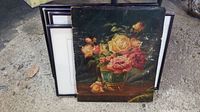 Five pieces of artwork stacked, showing one unframed floral painting with pink and yellow roses in a green vase and visible scratches.
