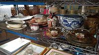 Shelf view showing assorted porcelain plates, bowls, tea sets, Satsuma vases and blue and white planter
