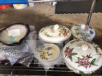 Three lidded porcelain soup tureens with floral motifs and one small plate