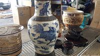 Three items displayed together: blue and white porcelain vase, Satsuma-style jar on stand, turquoise planter