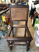 Front view of vintage wooden chair showing cane backrest and empty seat frame with detailed carved edges