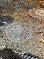 Cut glass serving bowls and trays shown on granite countertop highlighting intricate etched and cut patterns