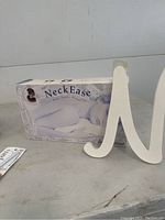 Photo showing NeckEase neck support pillow box, large wooden letter N