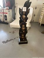 Front view of carved wooden three wise monkeys statue showing the three monkeys stacked and the square base.