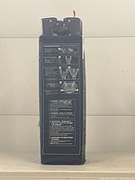 Side view of the folded black Cosco pack and play showing detailed printed safety instructions and usage guidelines.