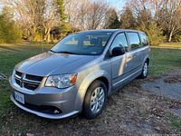 Front three-quarter view of a silver 2014 Dodge Grand Caravan parked on grass