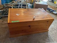 Front and top view of the pine wood chest showing flat lid and knob handle with wood grain and knots.