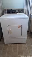 Front view of white Kenmore dryer with visible wear and torn door label