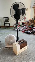 Full view of the three items on carpet: black floor fan, white desk fan, and Sunbeam humidifier.