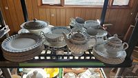 Full set of Johnson Bros Snowhite Regency china including plates, bowls, cups, saucers, teapot, sugar bowl, creamer, gravy boat, serving bowls, covered serving bowl, and platters shown on shelving.