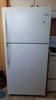 Front view of white Whirlpool top freezer refrigerator with dual vertical handles.