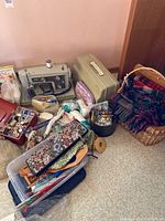 Full lot view showing sewing machine, sewing supplies, two wicker baskets with blankets, and other craft items