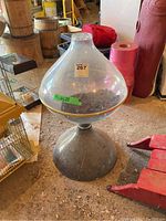 Full view of the vintage plastic terrarium showing clear dome with orange trim seated on a black base, dusty and stored in a cluttered environment.