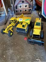 Front view of all three Tonka toys together showing grader, dump truck, and bulldozer