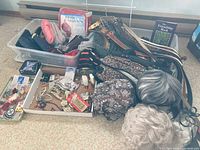 Wide view photo showing the entire lot including wigs, belts, jewelry, scarves, slippers, and handbags arranged on the floor.