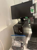 Photo of Acer monitor on top of Dell computer tower with headphones in a plastic bag at the base.