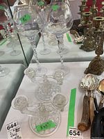Photo showing two glass candle holders and two tall glass decor glasses with twisted stems, reflections on mirrored surface.