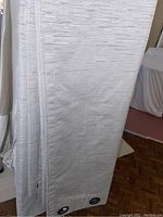 Five white drapery panels hanging, shown front face with textured horizontal lines and metal grommets visible at bottom edge in one image
