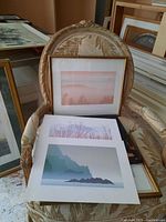 Four limited edition prints laid out on a chair and surface, including a framed print with broken glass and three unframed prints.