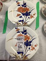 Photo showing two stacked octagonal Mikasa salad plates with floral Fushimi pattern, highlighting colorful orange and blue flowers and gold accents on cream background.