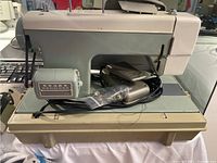 Front side view of the Sears Kenmore sewing machine model 5188 showing the heavy metal body, sewing arm, power cord and foot pedal placed on the base platform.