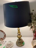 Pair of matching table lamps with heavy metal bases and dark drum lampshades shown on a table among decorative items.