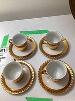 Four Thun espresso cups and saucers viewed from above, showing gold accents and white ceramic.