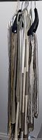 Eight unfinished curtain panels hanging on clothing hangers shown folded and draped together, showcasing various neutral tones.