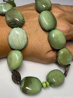 Close-up of the green stone beads showing color, natural markings, and texture, along with the hammered sterling silver spacers.