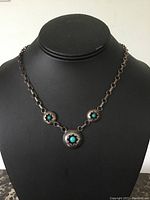 Front view of the necklace on display bust, showing three round turquoise stones set in silver bezels connected by a silver chain with round links.