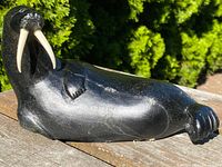 Side view of the entire soapstone walrus sculpture revealing curved body and tusks