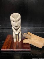 Front view of carved bone implement and carved wood tool on wooden base