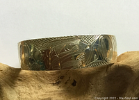 Front view of the sterling silver cuff bracelet laid on wood showcasing detailed eagle carving and texture.