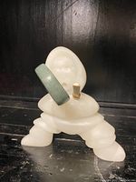 Front view of white soapstone Inuit figure kneeling with drum