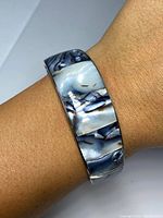 Bracelet worn on wrist showing abalone shell inset pattern and metal finish.