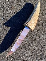 Full knife laid on asphalt showing handle, sheath, and blade