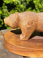 Side view of wooden carved bear sculpture showing detailed wood grain texture and surface wear.