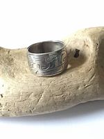 Front side view showing hand carved Northwest Coast design and silver surface.
