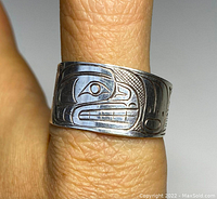 Close-up of the ring on a finger showing engraved animal face design and silver tarnish.