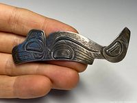 Front angled view of the Northwest Coast sterling silver brooch showing intricate engraved design and overall shape.