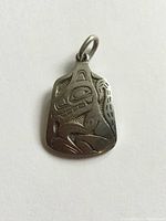 Front view of silver wolf pendant showing stylized indigenous art design detailing.