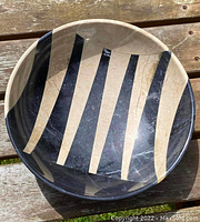 Top view of a circular stone bowl showing black and beige vertical striped geometric pattern.