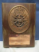 Front view of the wooden plaque showing bronze emblem and dedication plate