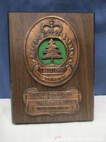 Full frontal view showing the wooden plaque with bronze military emblem and dedication plate