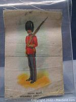 Full view of antique tobacco silk depicting a soldier in red uniform with rifle and bearskin hat.