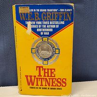 Front cover of the book showing the title 'The Witness' by W.E.B. Griffin with a worn yellow background and a torn sticker.