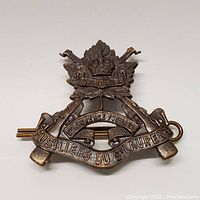Front view of bronze St Laurence Fusiliers cap badge with detailed maple leaf, King’s crown, and crossed rifles iconography.